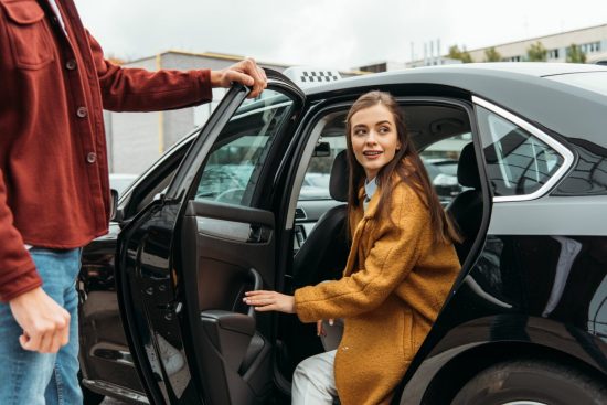 taxi-driver-opening-car-door-for-smiling-woman-1536x1025